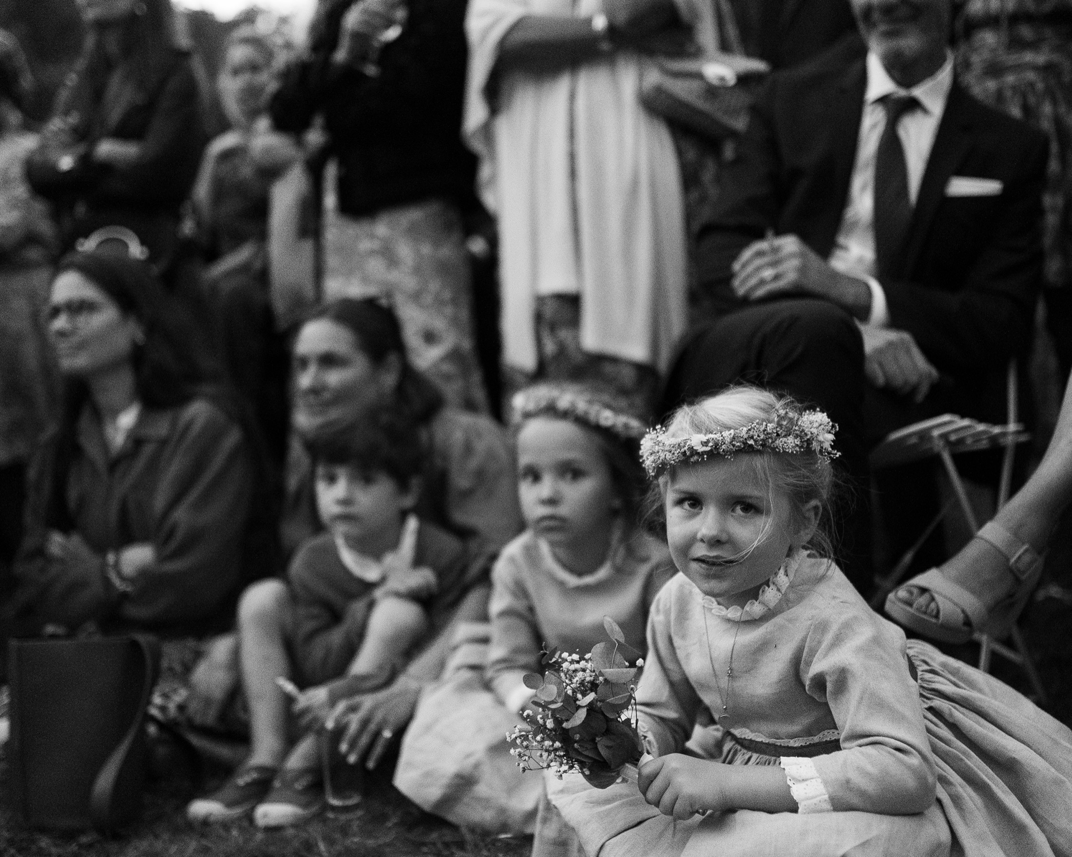 Une enfant d'honneur en couronne de fleurs pendant la cérémonie, en noir et blanc